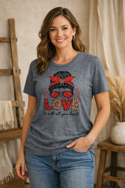 Woman wearing a gray Love is All You Need Tee, standing in a home setting.