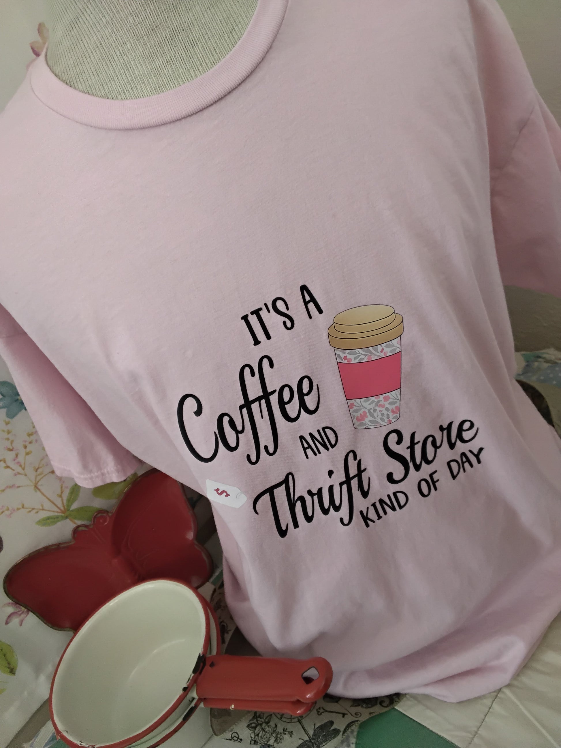 It’s a Coffee and Thrift Store Kind of Day Tee in Light Pink on a background decorated with a butterfly tray, ribbon and old pans